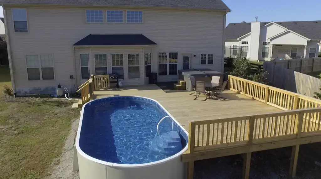 Oval above-ground pool wrapped by a new wood deck