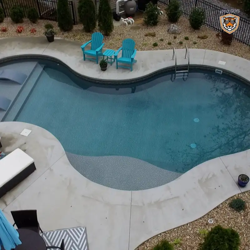 Freeform pool with a sun shelf and teal Adirondack chairs on the deck