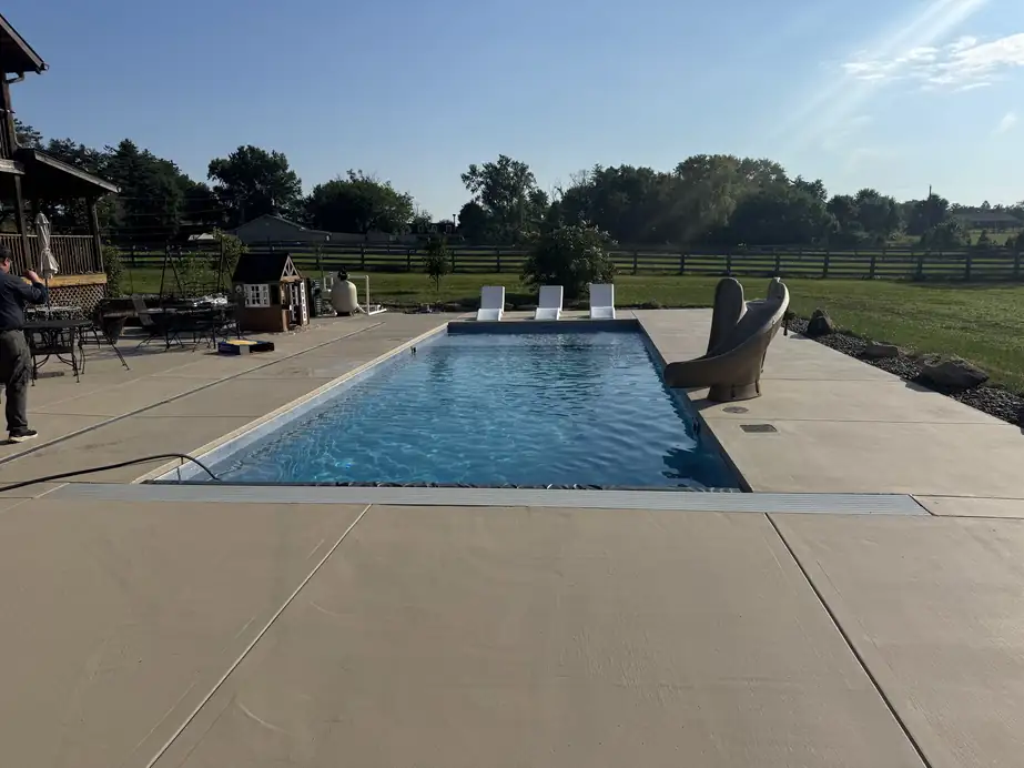 Long rectangular pool on a broom-finish concrete deck with open Kentucky farmland behind