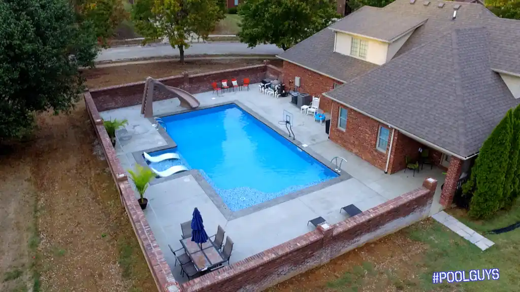Pool inside a brick-walled yard beside a brick home